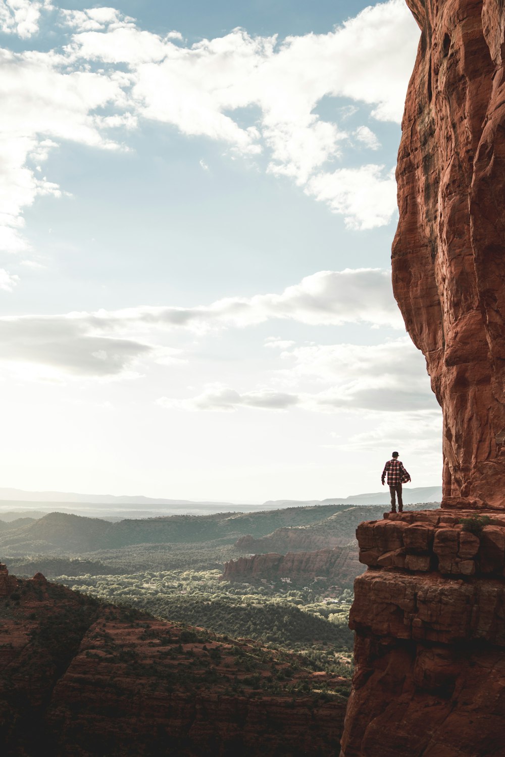 man standing on cliff during cloudy day