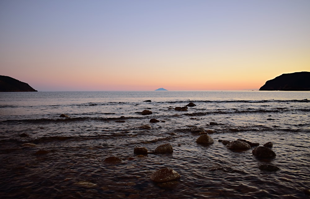 grey stones on shore during sunset