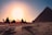 five persons riding camels walking on sand beside Pyramid of Egypt