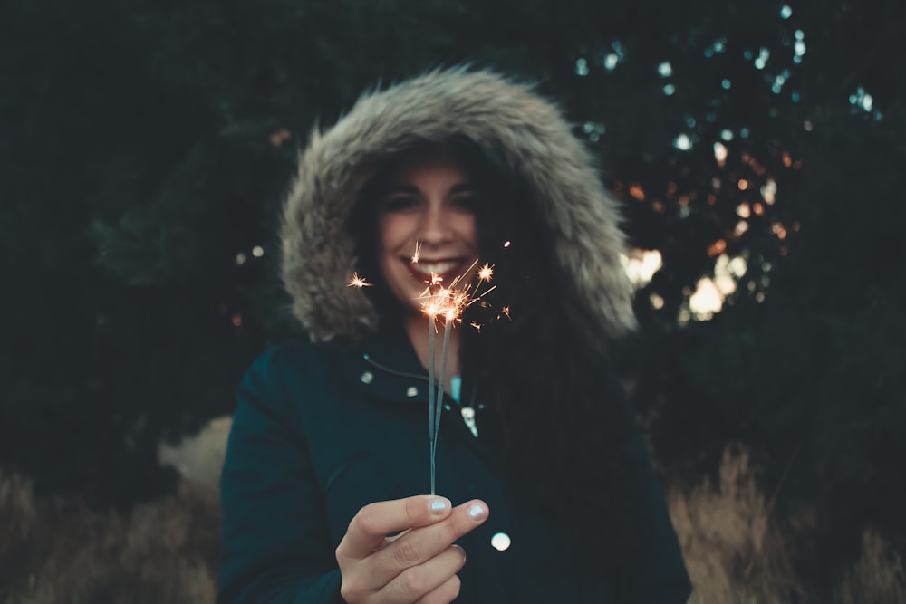 woman in fur-trim coat holding sparkler