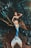 A woman dressed as a mermaid with a brightly colored tail lies on a tree trunk in a dense, lush forest. The mermaid's scales display vibrant shades of blue and orange, contrasting with the earthy tones of the surrounding foliage. She is adorned with leaf-like coverings and has an elegant pose, emphasizing a mythical and fantasy theme.