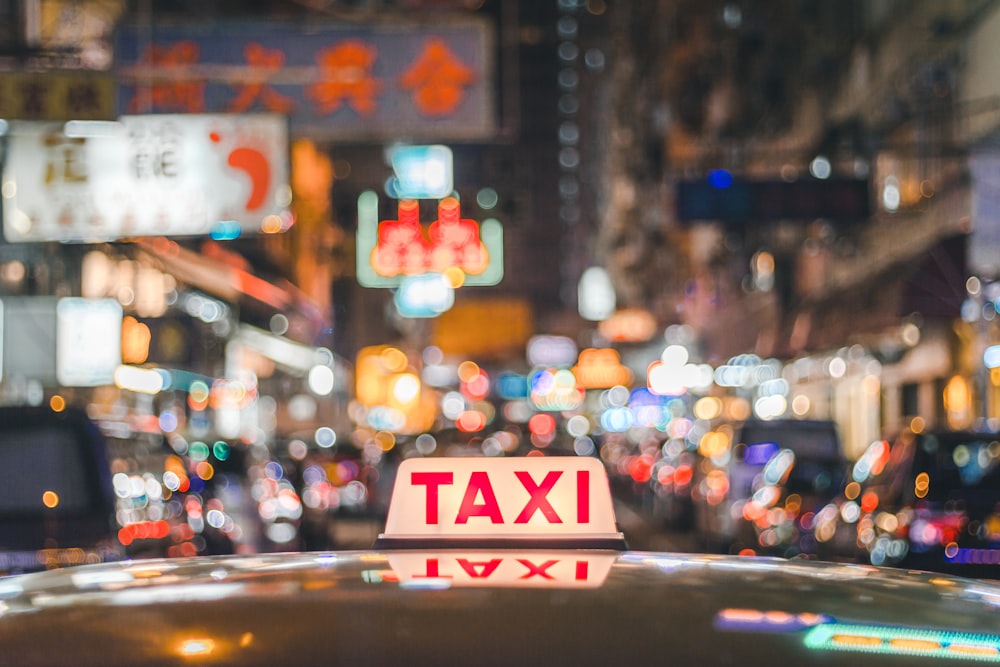 selective focus photo of red and white Taxi sign