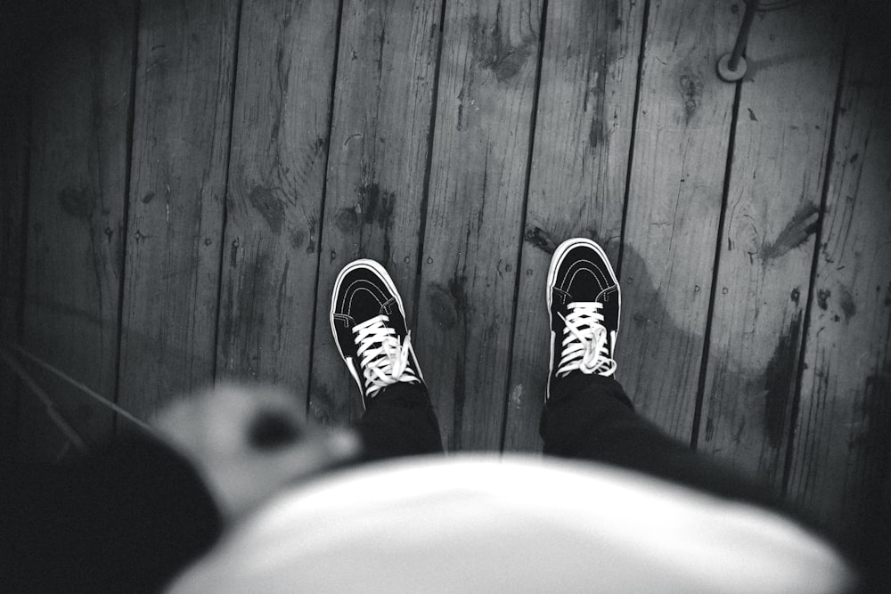grayscale photo of person wearing Vans shoes