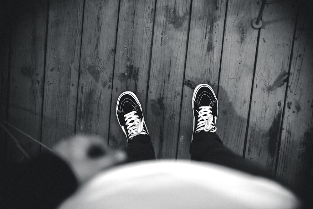 photo en niveaux de gris d’une personne portant des chaussures Vans