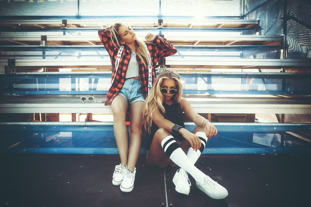 squatting woman beside woman in red and black checked top