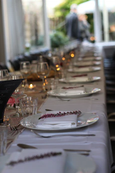 An elegantly set restaurant table with red and white checkered tablecloth, softly lit by candlelight.