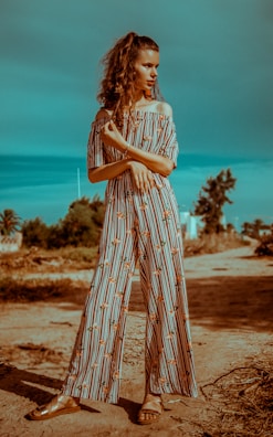 A relaxed fit jumpsuit in earthy tones, styled with minimalist sandals and a delicate necklace, posed outdoors.
