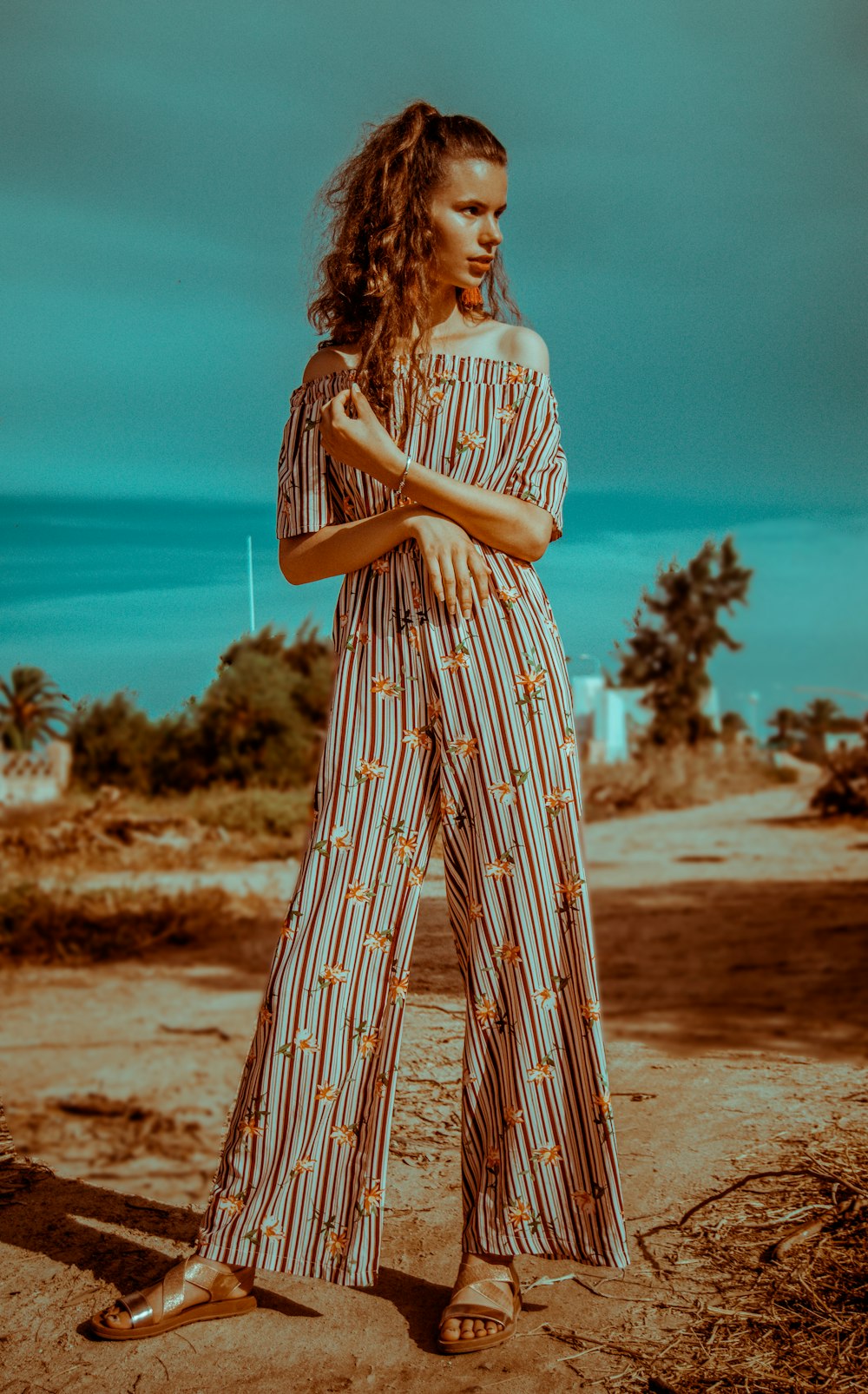 woman in brown overalls standing crossing arms at daytime