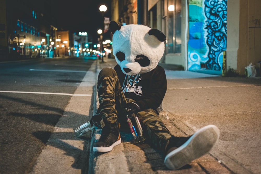 man wearing panda costume leaning on post