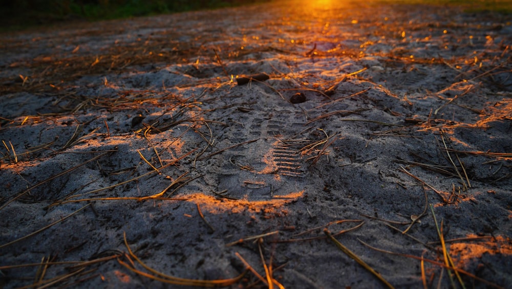 the sun is setting over a dirt field