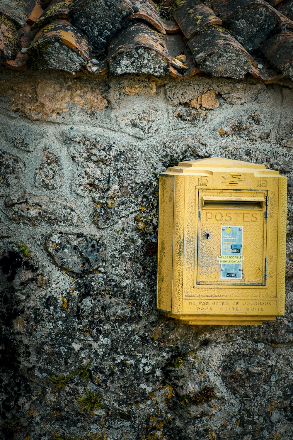 yellow mail box hung on gray wall