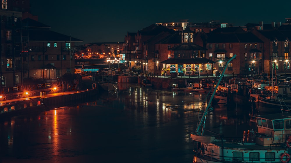 boat at dock by buildings with lights during nighttime