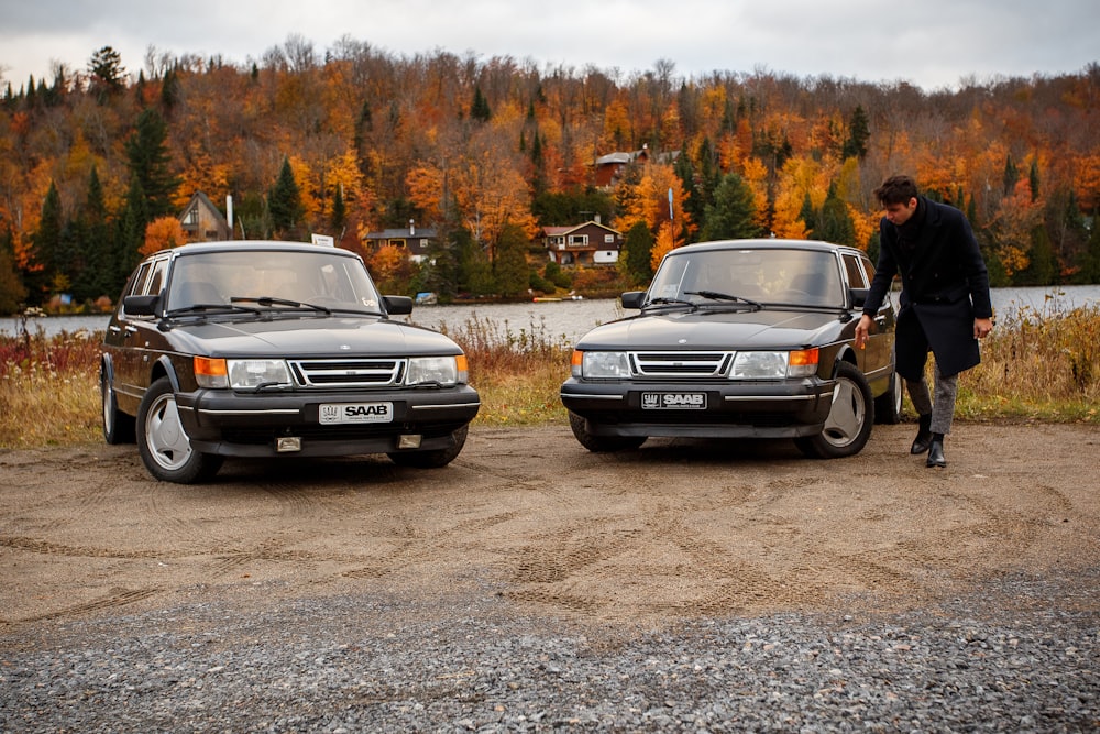 man standing beside two parked vehicles during daytime