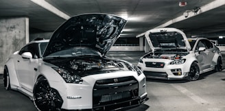 two white cars with open hoods