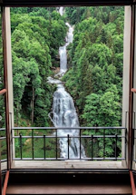 A person filling out a contact form near a window with flowing mountain water visible outside.
