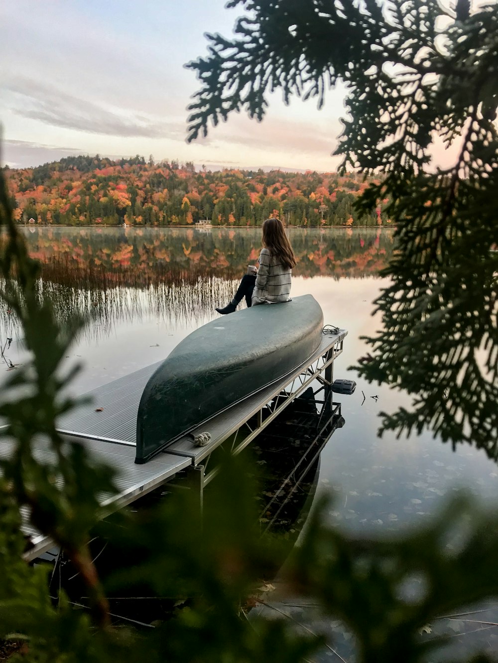 woman in sweater sits on green boat on dock