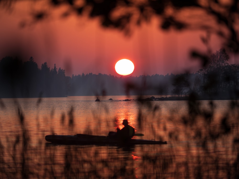 boating man on calm water during golden hour