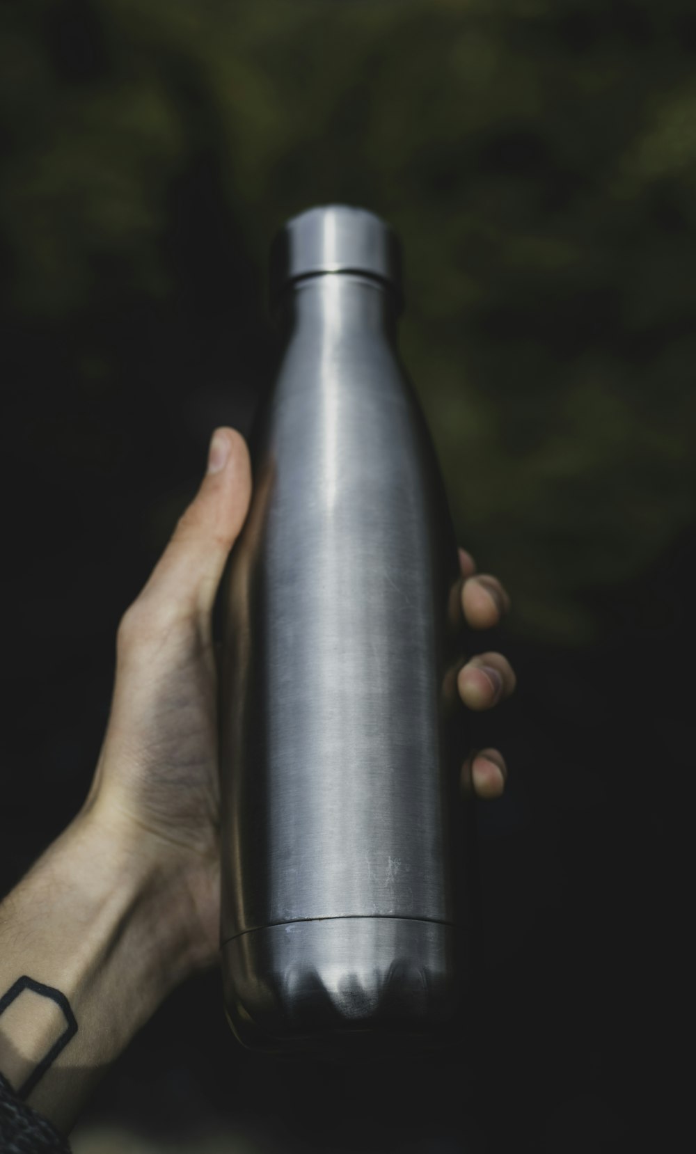 Persona sosteniendo una botella gris