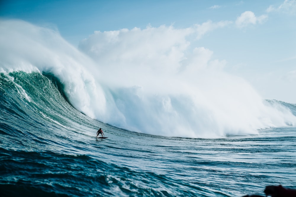 persona montada en tabla de surf con olas detrás