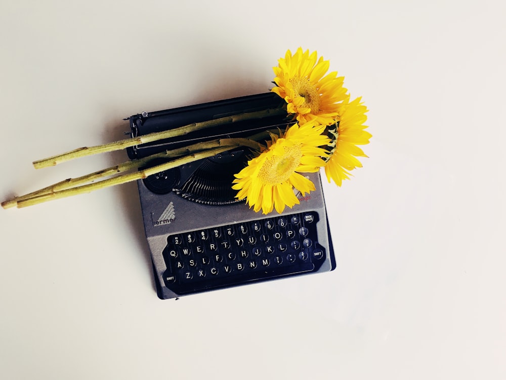 Máquina de escribir negra con flores amarillas en la parte superior