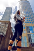 A confident model striking a dynamic pose against a cityscape backdrop.