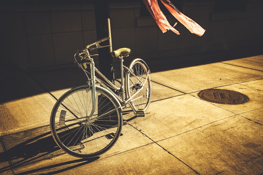 bicicleta de paso gris apoyada en un poste negro