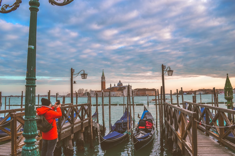 man using smartphone standing near two boats