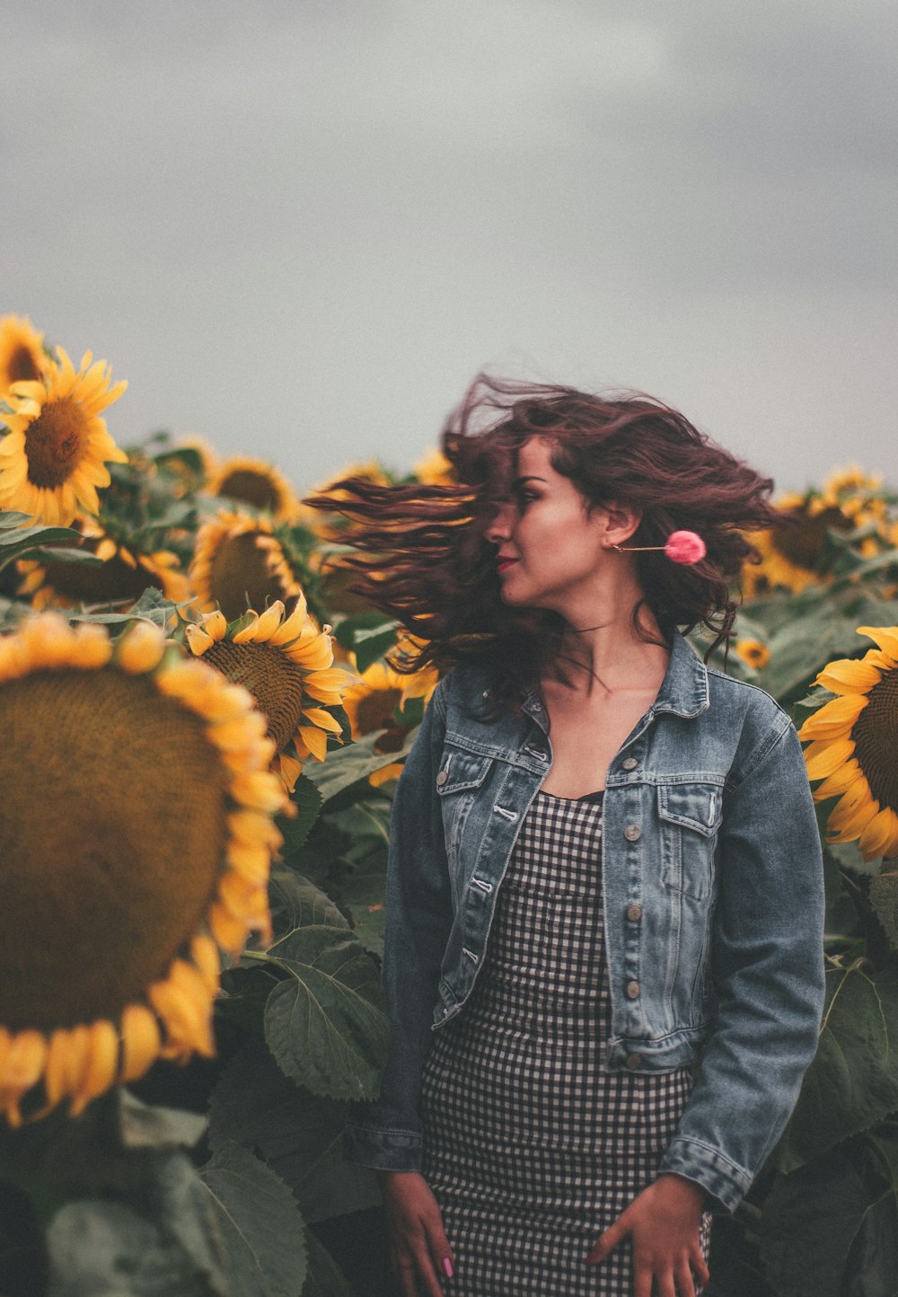 woman wearing blue denim jacket standing on sunflower field