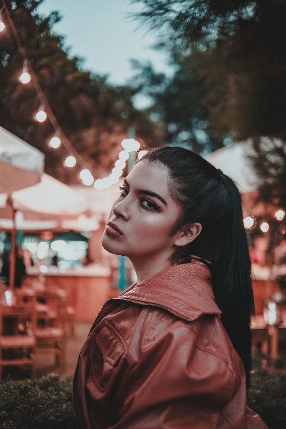 woman wearing brown leather jacket standing and facing her left side