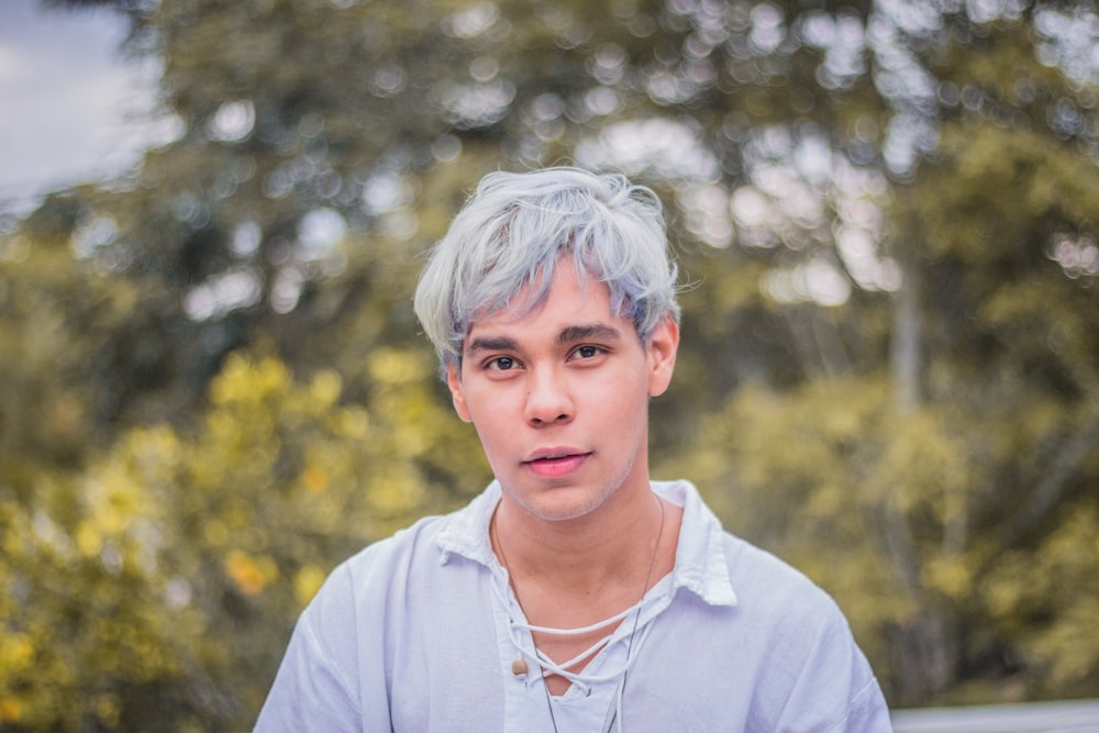 selective focus photography of man in white collared top near trees