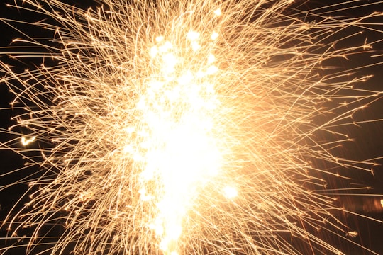 A glowing gold lottery ball bursting with confetti against a dark background.