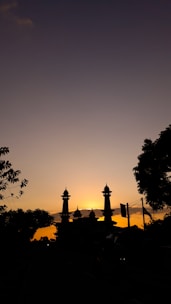 A serene mosque silhouette at sunset with intricate Islamic geometric patterns framing the scene.