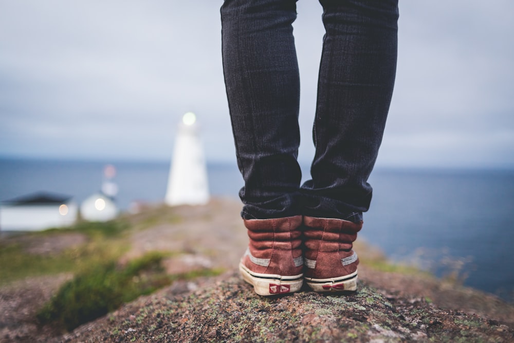 person in black pants and maroon shoes standing on hill