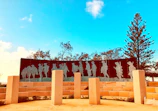 A solemn memorial wall etched with names of fallen American service members under a clear blue sky.