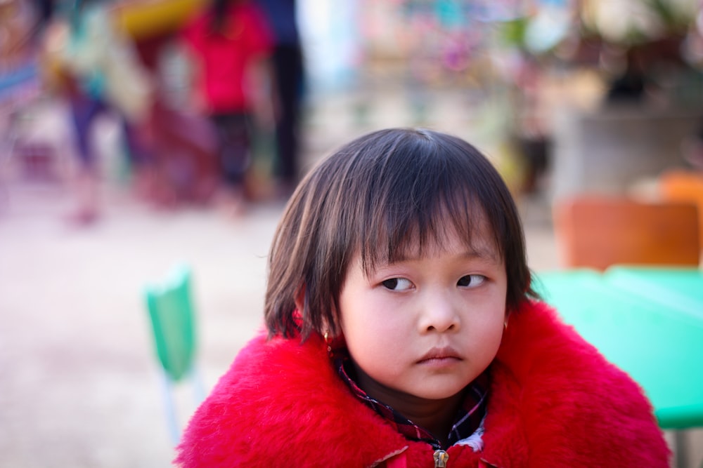 tilt shift focus photography of girl in red fur coat