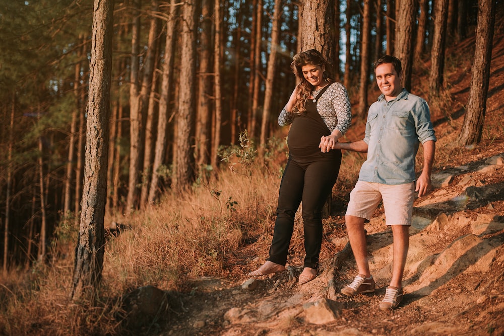 man walking beside pregnant woman under trees