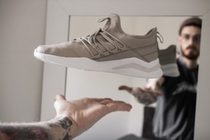 person showing unpaired gray and white running shoe