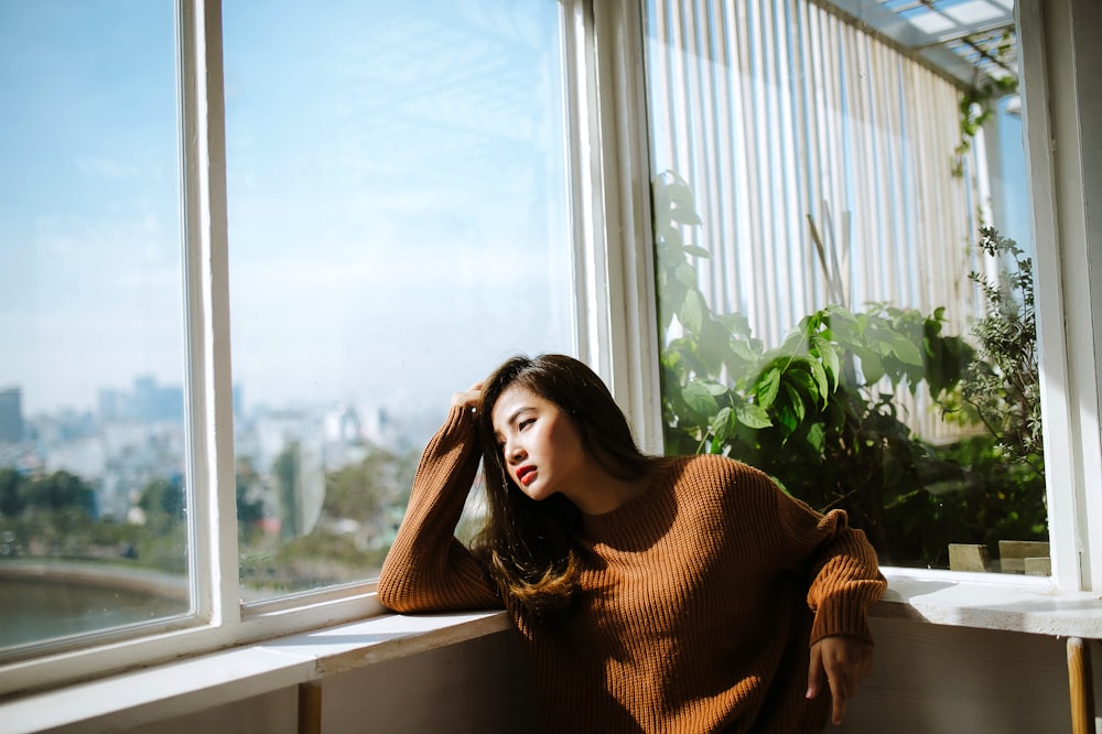 woman leaning on white wooden framed clear glass wall