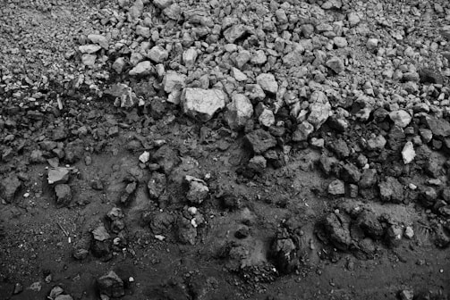 A monochrome image depicting a rocky and uneven surface with various sizes of stones spread across it, transitioning from rough to smooth textures toward the bottom.