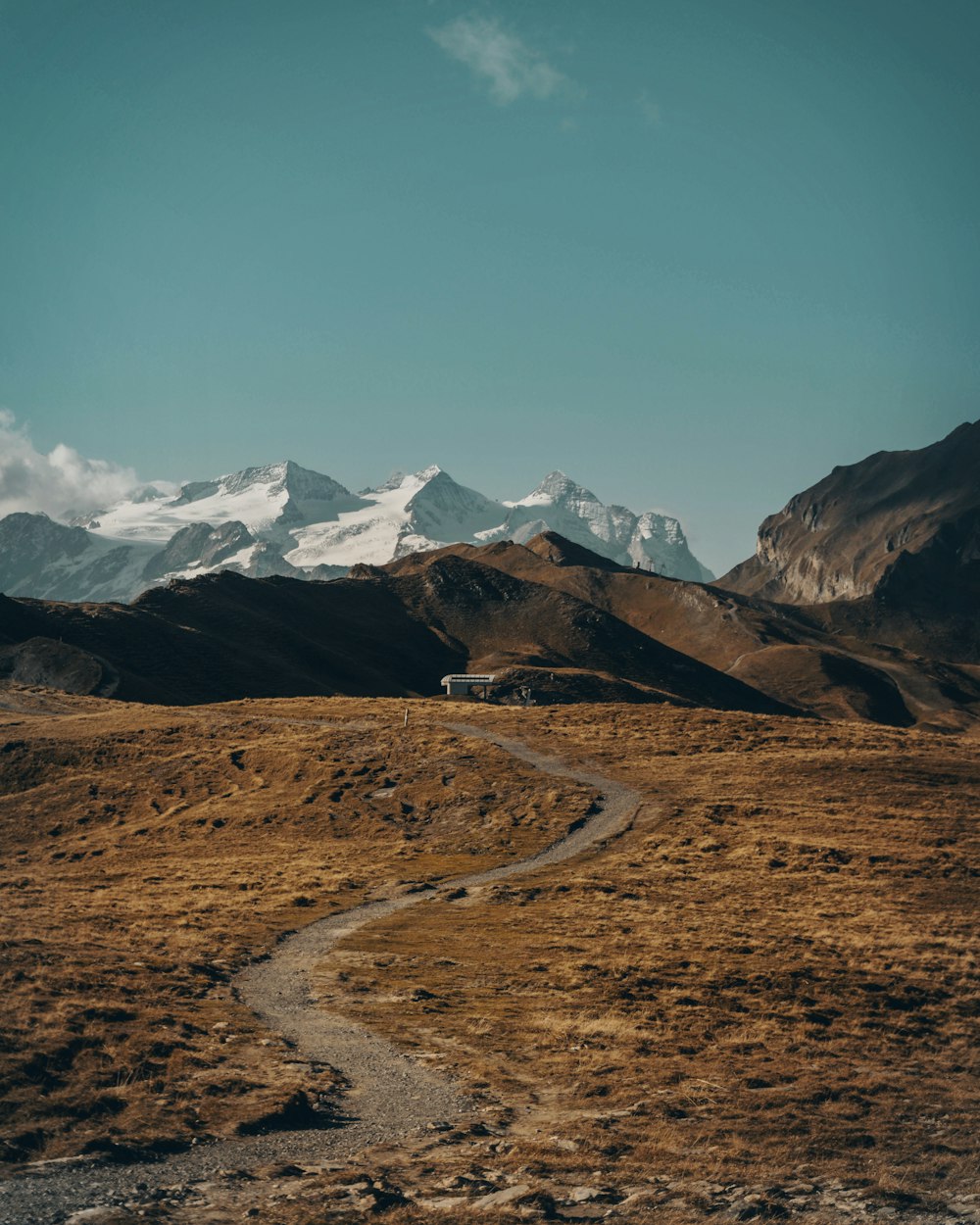 dirt road between open field with mountain range in background during daytime