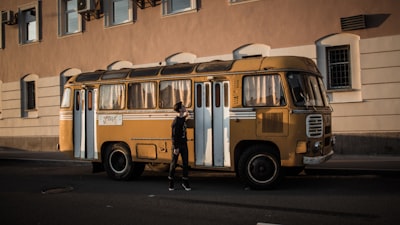 man standing beside yellow bus old-fashioned teams background