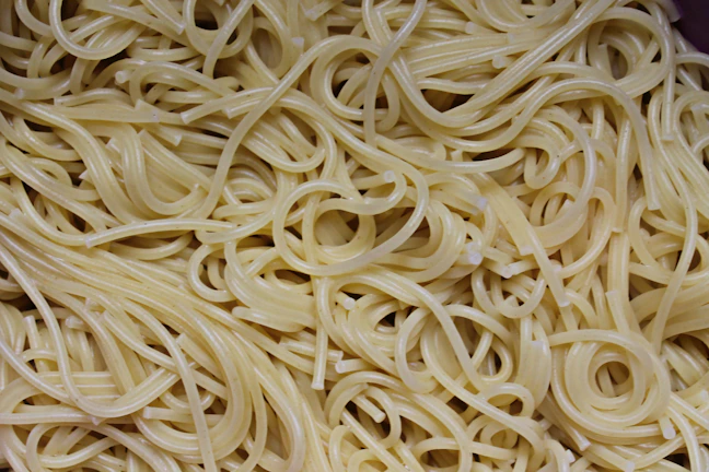 Close-up of freshly hand-pulled biangbiang noodles with chili oil glistening.