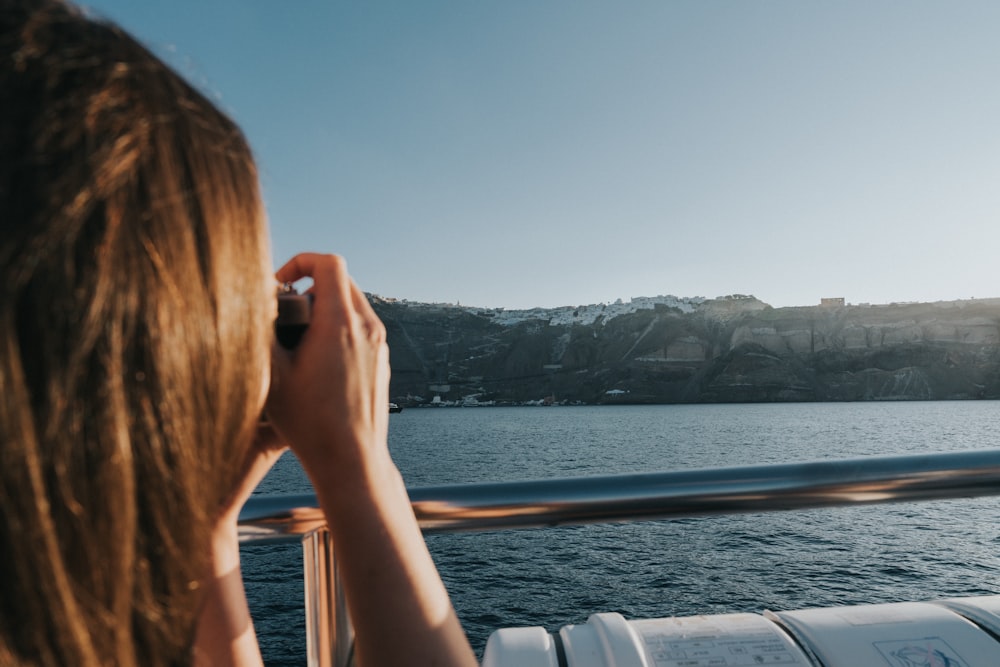 woman capturing photo while riding boat