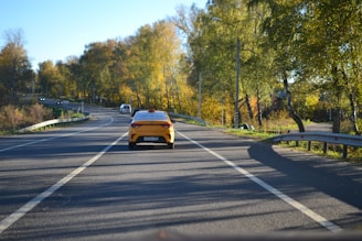 A yellow taxi on a scenic rural road surrounded by Oaxaca's green hills.