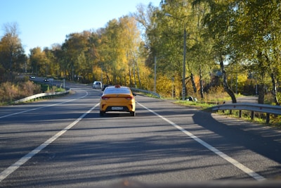 A yellow and black taxi driving on a scenic long-distance highway.