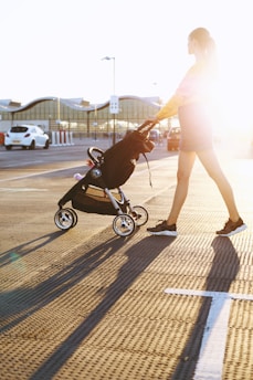 woman pushing baby's stroller on parking area