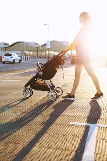 woman pushing baby's stroller on parking area
