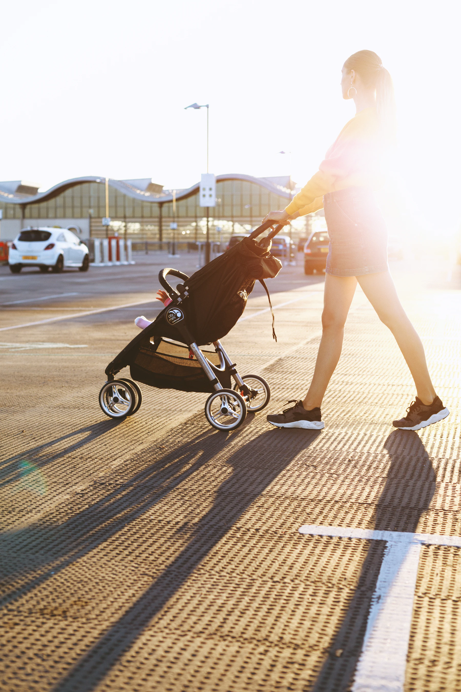 Woman pushing a stroller across a parking area