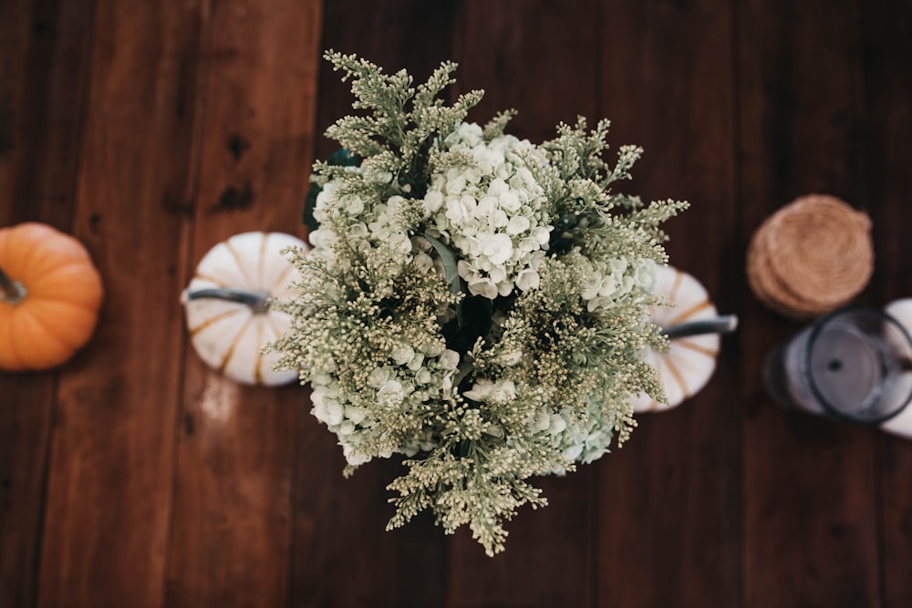 Decoración de mesa de plantas blancas y verdes sobre superficie de madera marrón