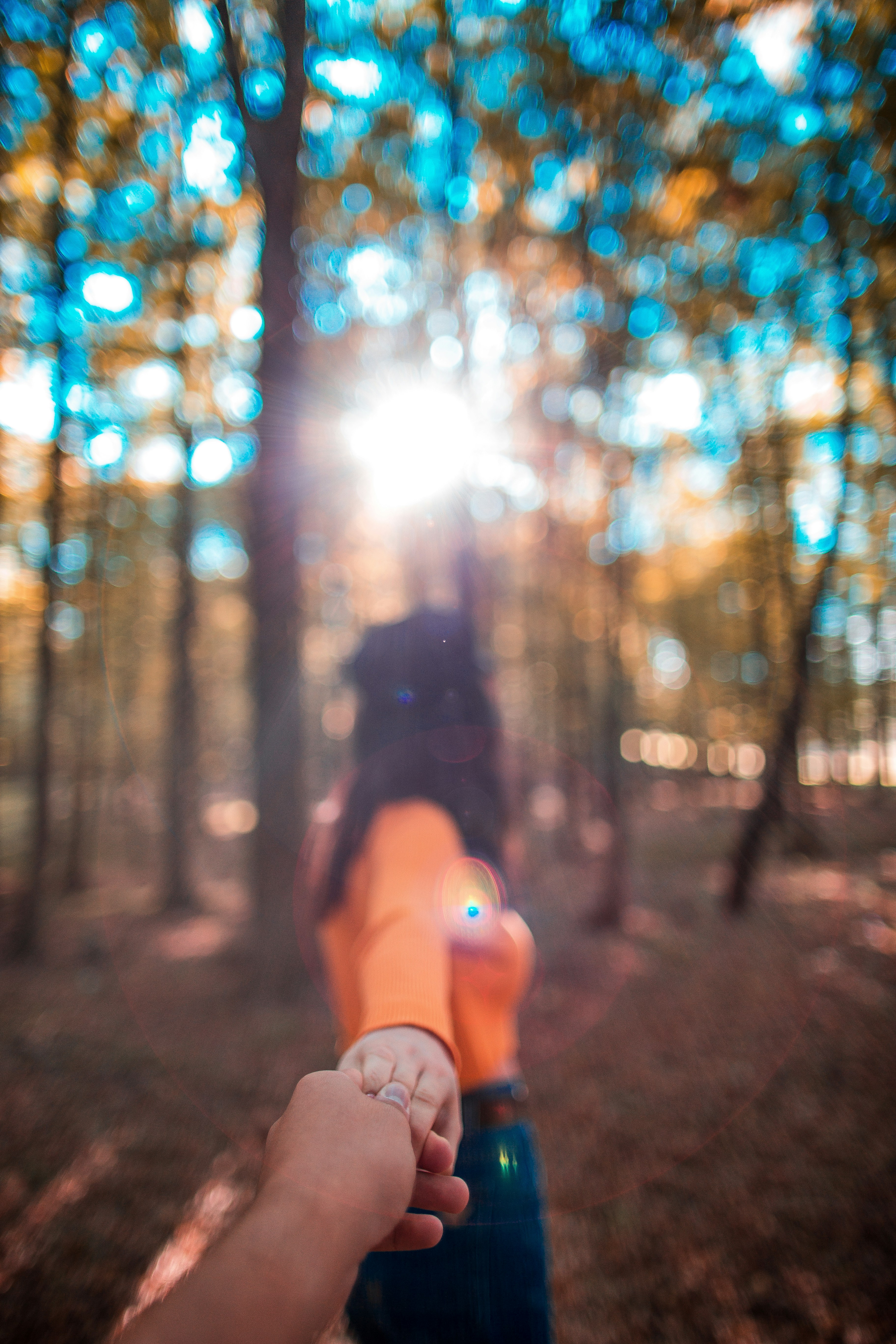 Couple walking hand in hand through a sunlit pathway, dreamy bokeh background, warm natural light